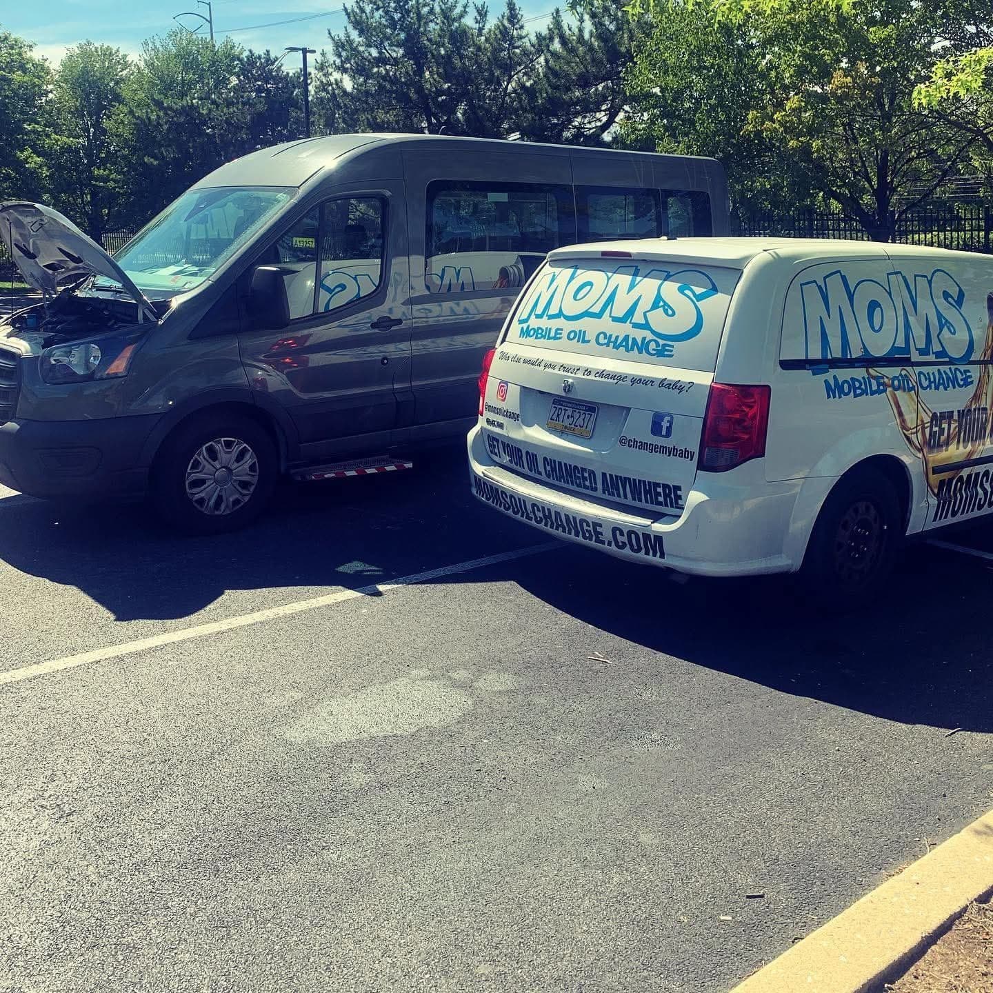 The MOMS van parked beside a fleet van with its hood up during an on-site service visit