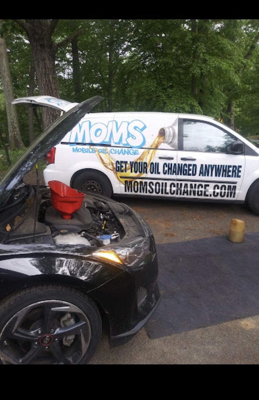 Oil change in progress on a sedan in a customer's driveway.