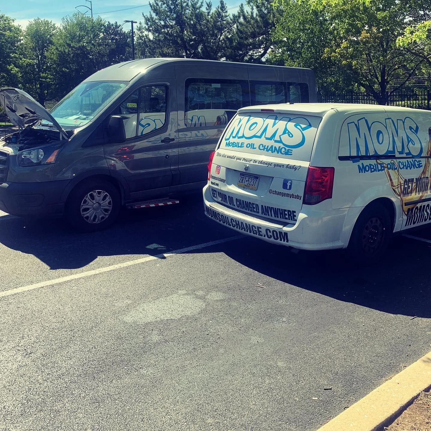 The MOMS van parked beside a fleet van with its hood up during on-site service.