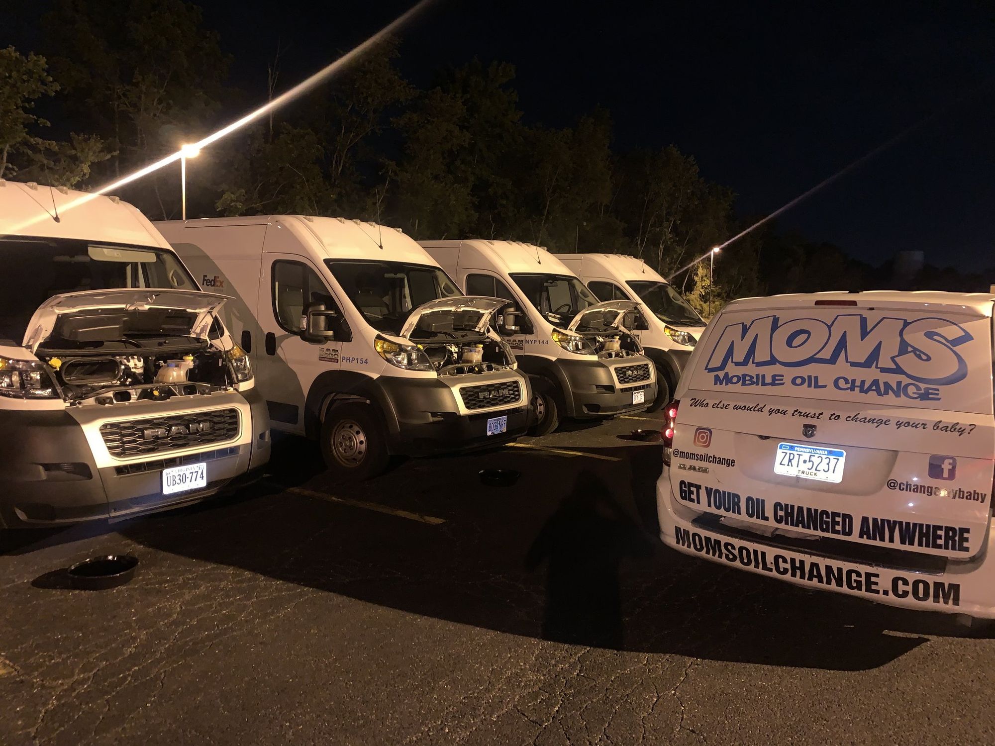 Night fleet service: the MOMS van beside a row of fleet vans with their hoods up.