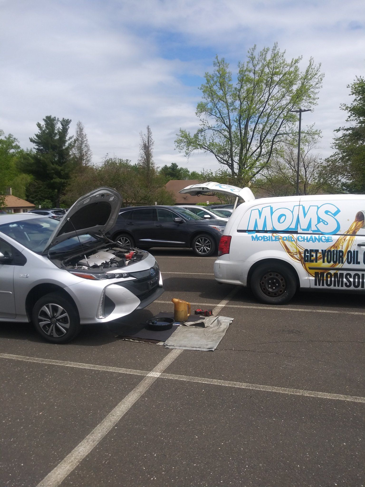 Oil change setup: drain pan and tools laid out beside a Toyota Prius.